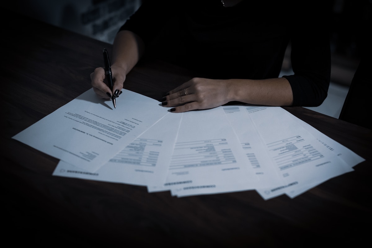 Mains signant des documents dans l'obscurité.