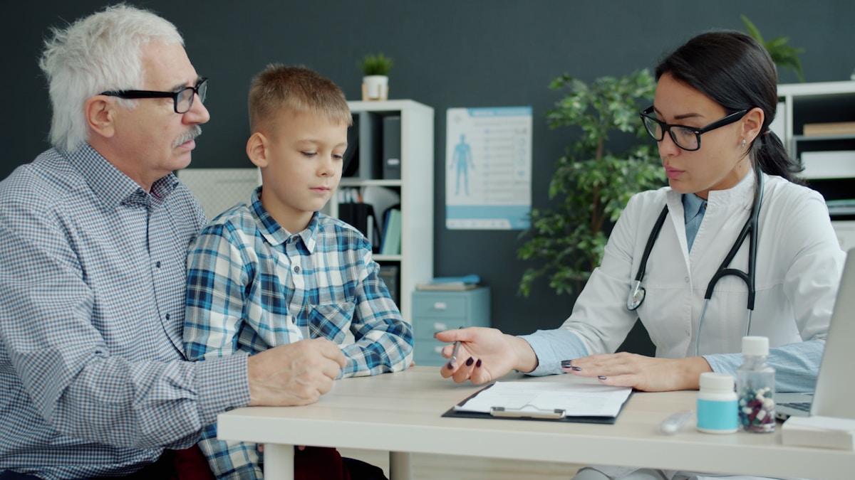 Médecin examinant un jeune patient avec son grand-père.