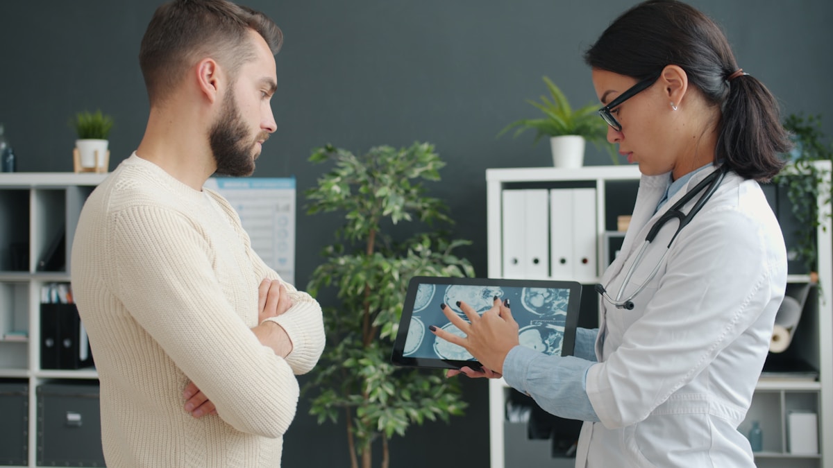 Médecin examinant un patient sur une tablette numérique dans un cabinet médical.