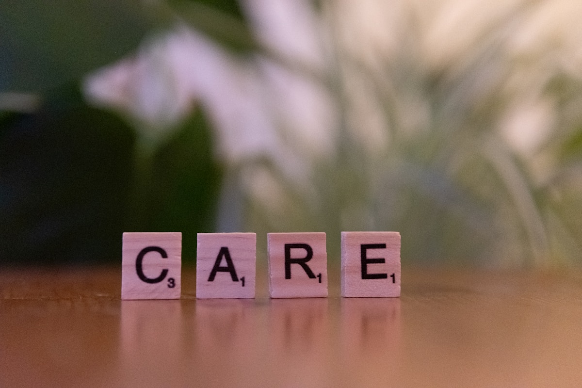 Lettres en bois épelant le mot "CARE" sur une surface en bois.