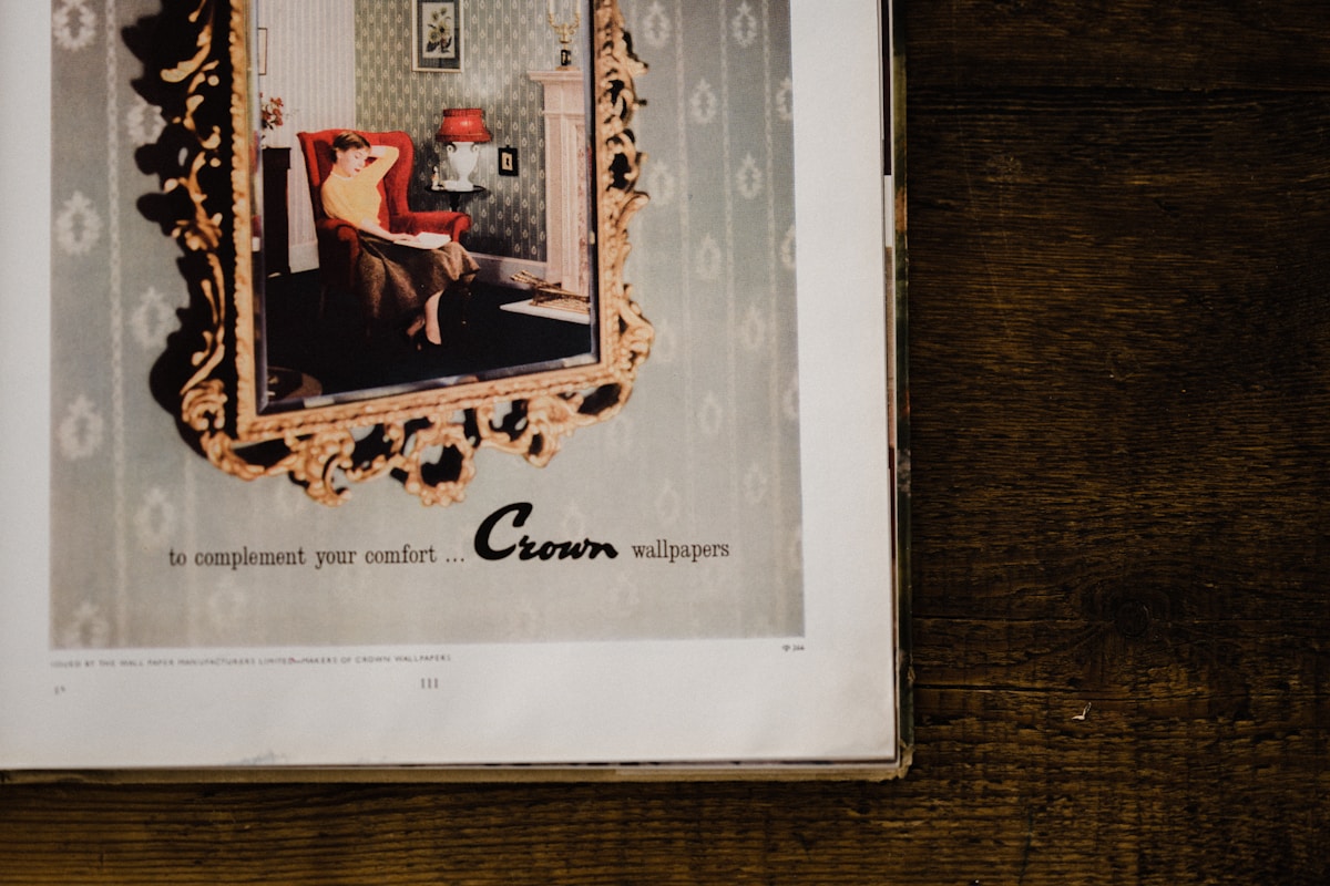Affiche vintage de papiers peints Crown, avec une femme assise dans un fauteuil rouge.