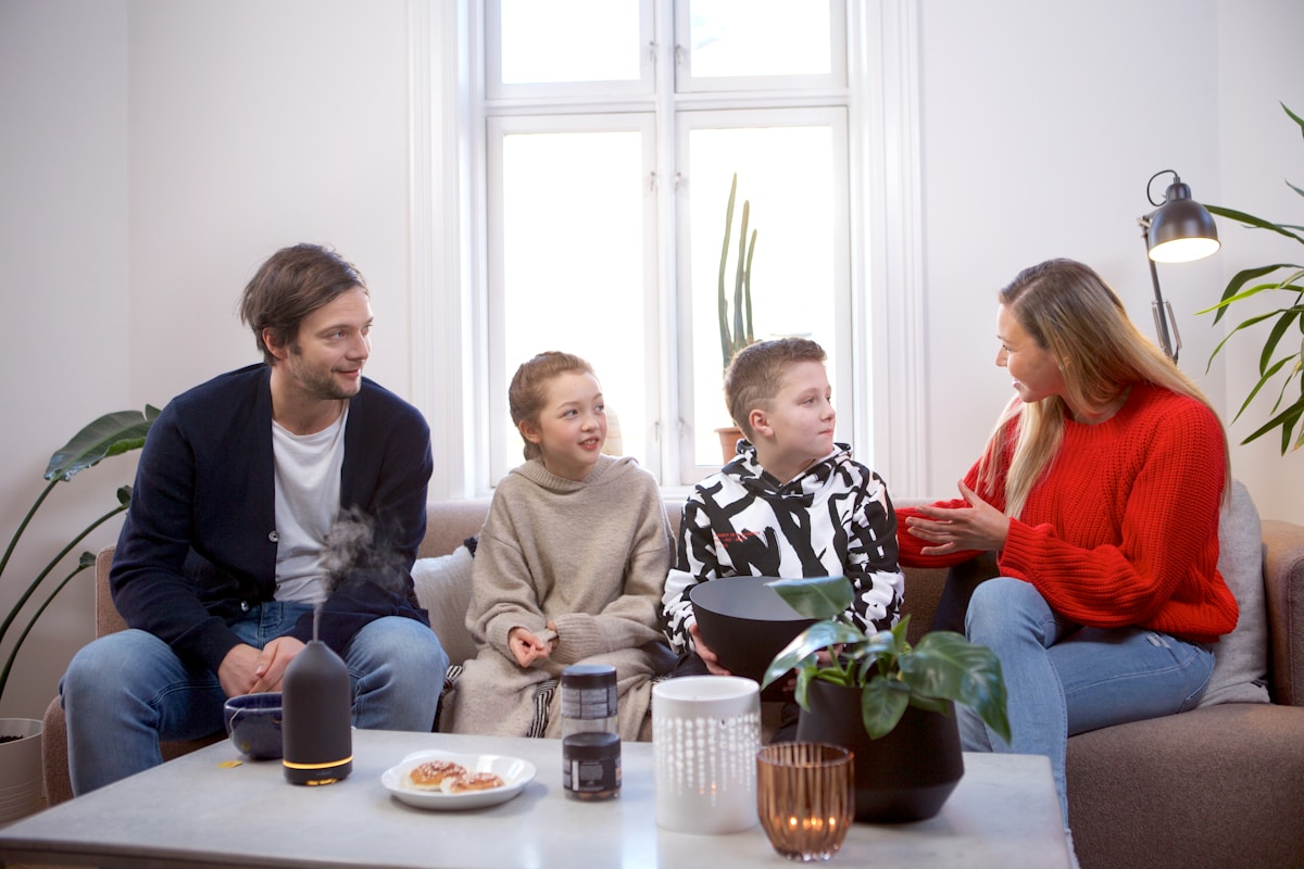 Famille unie discutant autour d'une table dans un salon lumineux.