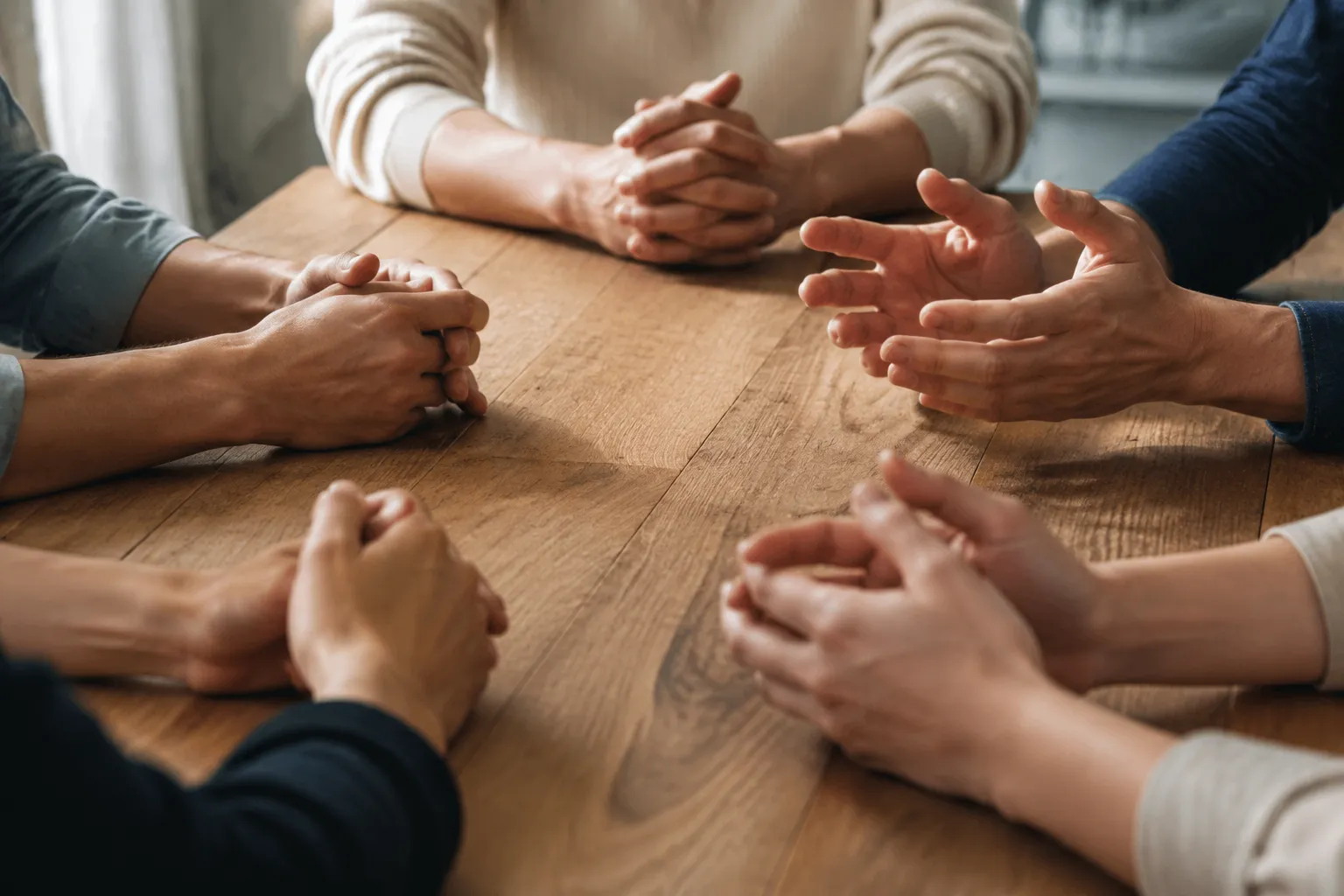 Mains jointes sur une table en bois, geste de soutien et de connexion.