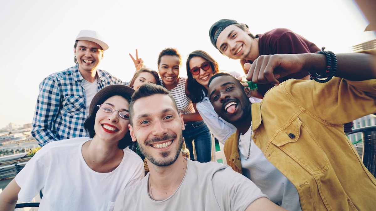 Groupe d'amis souriants et enthousiastes prenant un selfie ensemble.