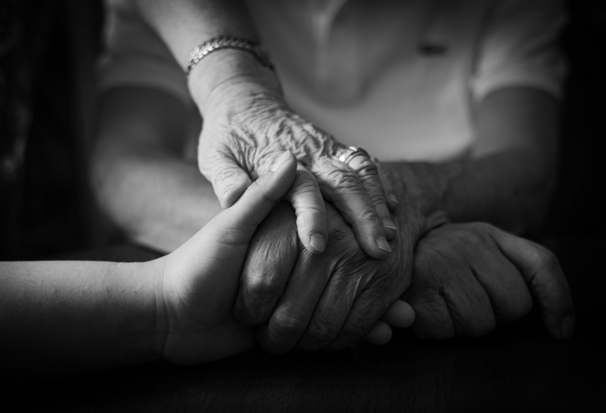 Mains âgées tenant tendrement les mains d'une personne plus jeune.