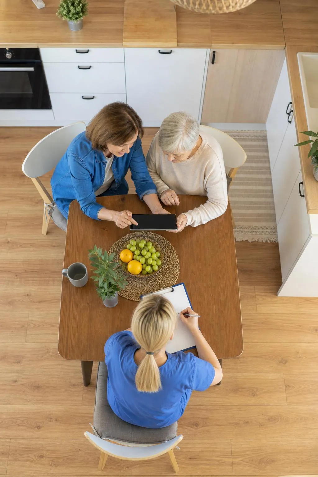 Deux femmes âgées utilisant une tablette numérique dans une cuisine moderne.