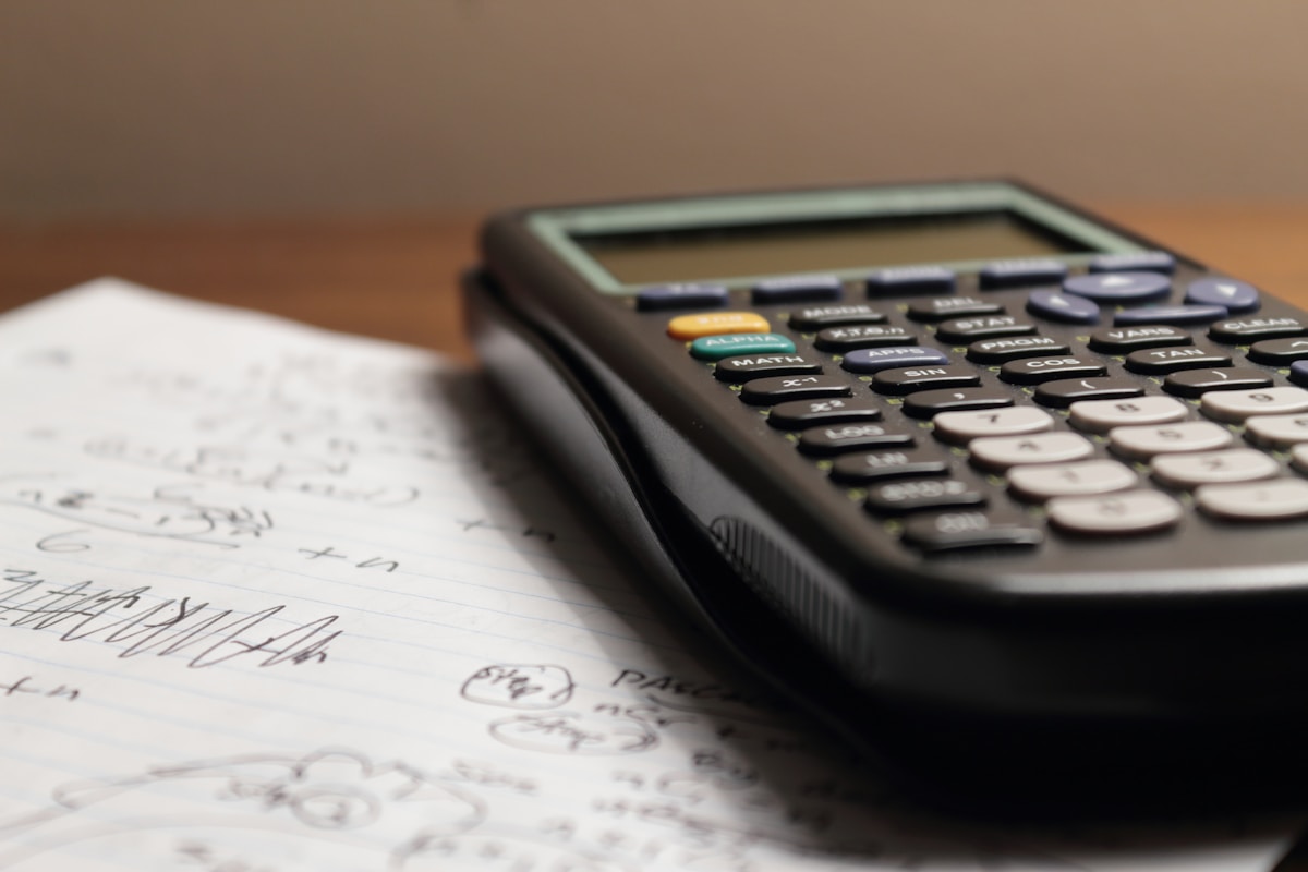Calculatrice et feuille de calcul sur un bureau en bois.
