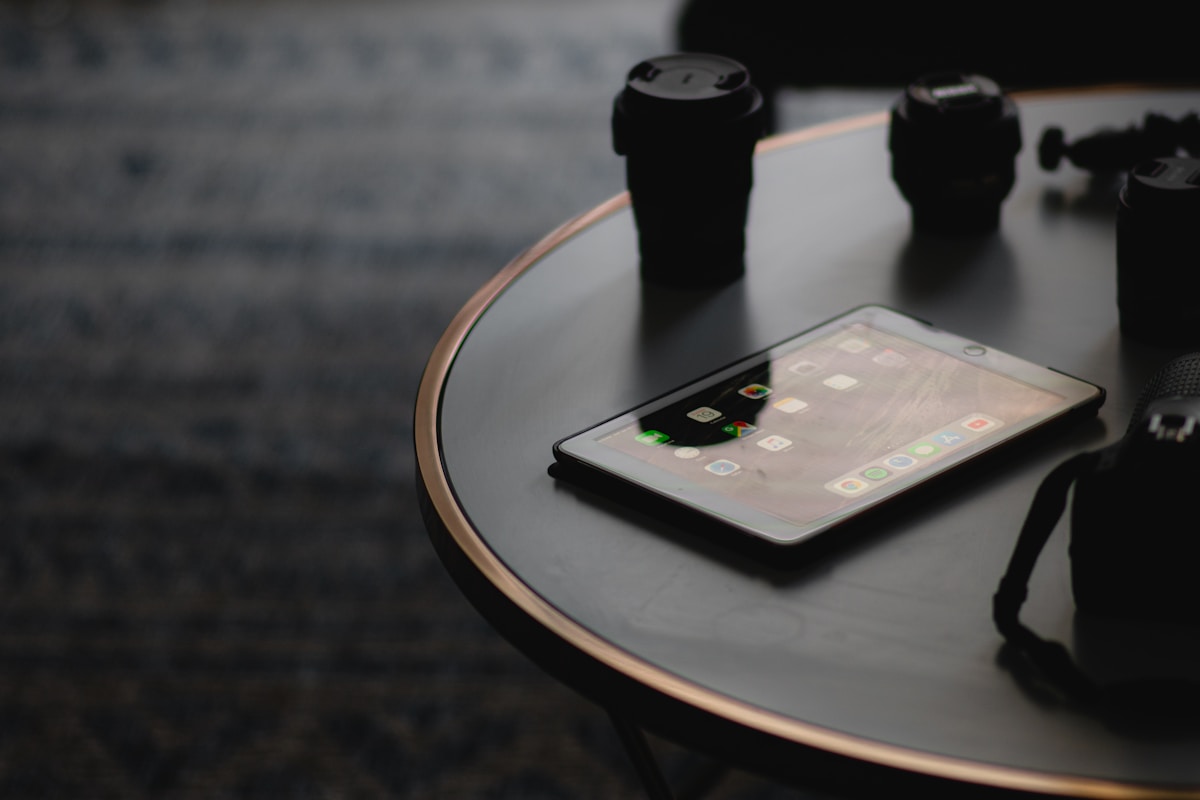 Smartphone posé sur une table ronde en verre sombre.