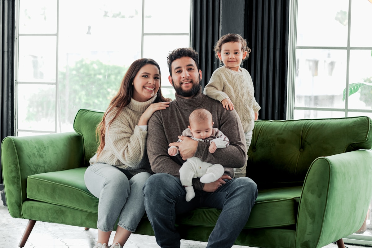 Famille heureuse sur un canapé vert, souriant ensemble.