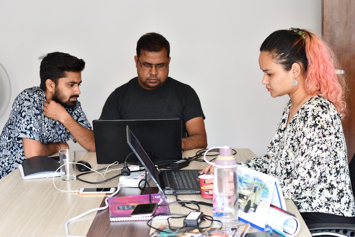 Trois personnes travaillant ensemble sur des ordinateurs dans un bureau.