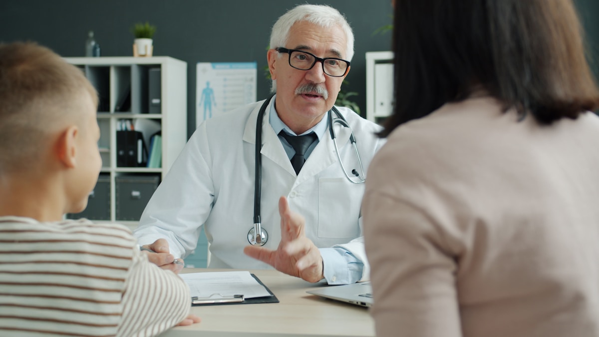 Médecin en consultation avec un patient et son accompagnateur.