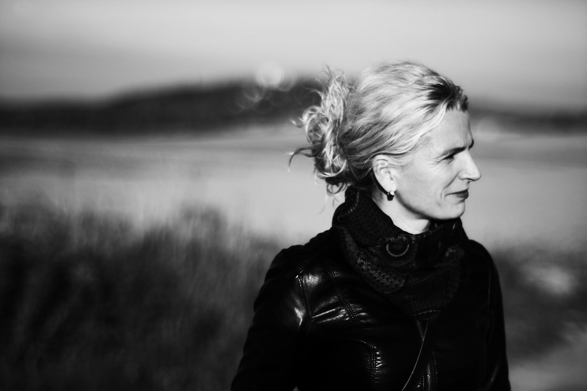 Femme aux cheveux blonds dans un paysage brumeux en noir et blanc.