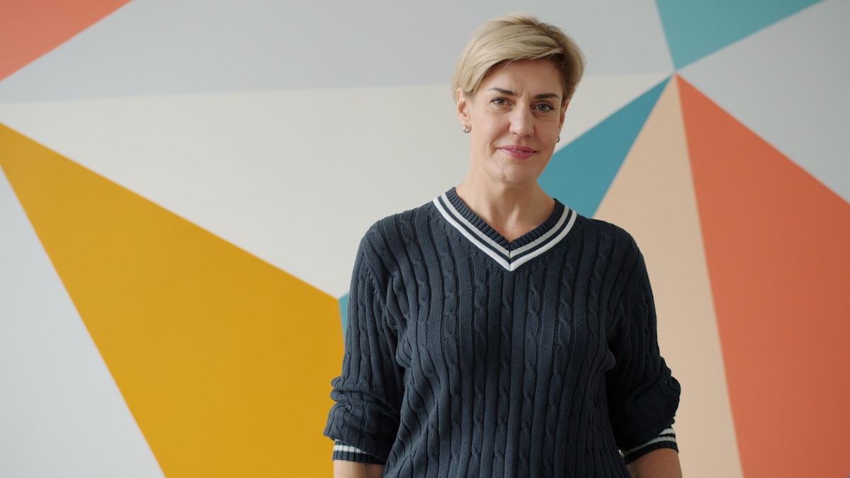Femme aux cheveux blonds portant un pull en maille côtelée.